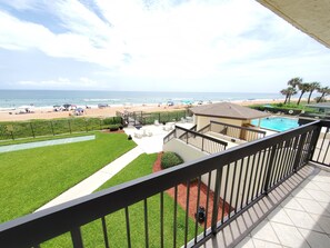 View from balcony overlooking beach and pool.
