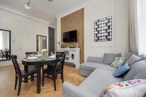 A different angle of the same living-dining room, showing two sofas, cushions, and wall art.