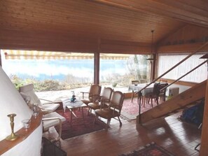 On the inside, there is a cosy main living room with open fire, a dining table, an integrated kitchen and a small bar. 