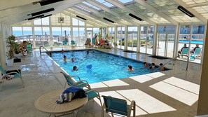 Glass enclosed indoor pool with views of the outdoor pool area and the gulf