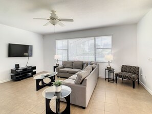 Modern living room with plush seating, flat-screen TV, and plenty of natural light.