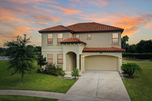 Stunning two-story home with a warm sunset backdrop and spacious driveway.