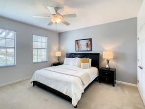 Bright and comfortable master bedroom with a king bed and ceiling fans.