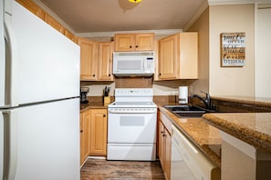 The kitchen features granite countertops, and is equipped with dishes, pots and pans, and cooking utensils.
