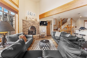 Living area featuring a large gas fireplace, TV, ample seating including a twin sleeper sofa, and sweeping mountain views!