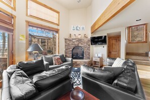 Living area featuring a large gas fireplace, TV, ample seating including a twin sleeper sofa, and sweeping mountain views!