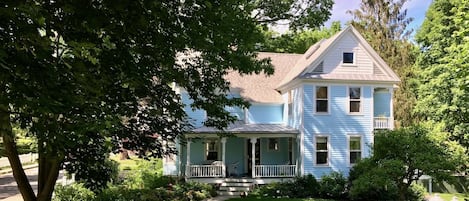 Summer view of front door and porch with rattan seating.