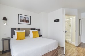 Relax in a stylish bedroom setup, where soft yellow accents on the pillows enhance the comfort of your king-sized bed, just steps away from the shower.