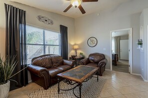 Kick back in this lovely living room with comfortable leather couches and ceiling fan for your comfort