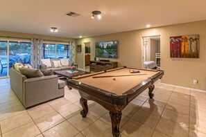 The cozy great room with plush furnishings features a pool table and TV.