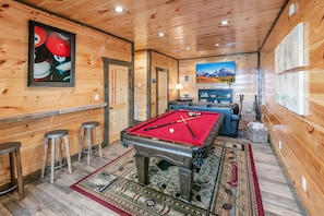 Lower game room with pool table, large screen TV, and sleeper sofa.