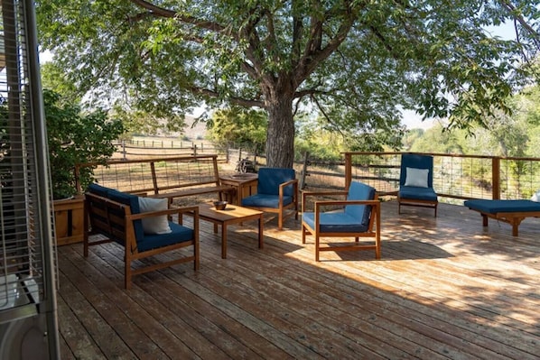 Large spacious wood deck with plenty of seating and shade tree.  Enjoy lounging out here and enjoying the views while conversing with friends or family.