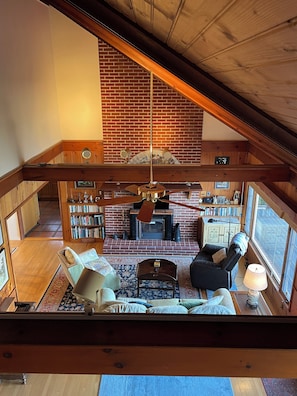 Two story living area with track lighting and dramatic cathedral wood ceiling.
