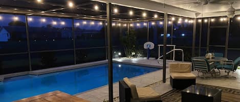 Professional landscaping and café lighting surround the covered pool and lanai