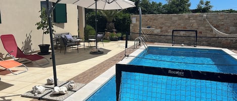 Blick auf den großen beheizten Pool mit Sonnenliegen & schöner Poolterrasse