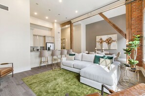Open-concept living, kitchen, and dining area with ample seating. Relax on a large sectional and enjoy a 65” Samsung Smart 4K TV with streaming and DIRECTV Entertainment. Dining table seats six, plus bar seating for four. Plenty of natural light!