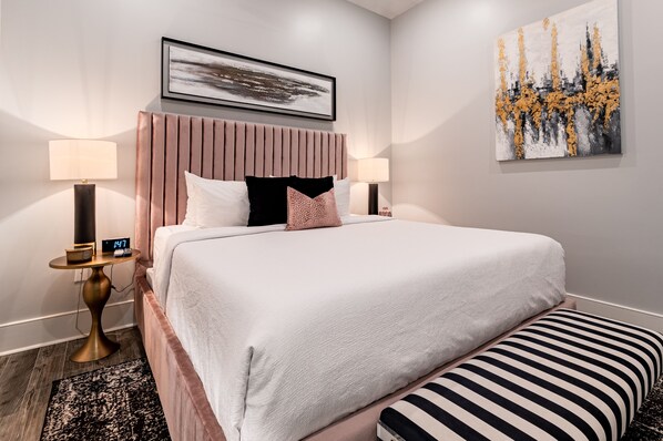 Spacious guest bedroom #1 featuring a king size bed and a designer built in closet. The bedroom is equipped with end tables, lamps, hangers, luggage rack, alarm clock, white noise machine