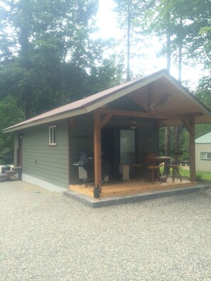 Front of cabin with table, and 4 chairs. there is a propane grill also.