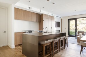 Fully equipped kitchen with seating for 4 in leather and wooden bar stools at the kitchen island