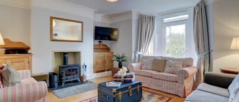 The cosy living area has 3 sofas, a wood burner for the cooler seasons, large wall mounted TV and glazed door to garden area