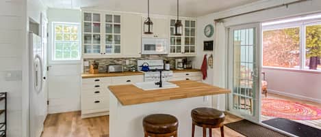 The full kitchen leads directly onto the screened-in porch. Kitchen Island from the dining table hand made by our neighbor, a talented woodworker. All the cooking space, utensils, cookware, and everything else you need, right there.