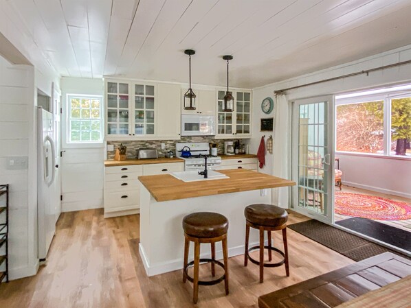 The full kitchen leads directly onto the screened-in porch. Kitchen Island from the dining table hand made by our neighbor, a talented woodworker. All the cooking space, utensils, cookware, and everything else you need, right there.