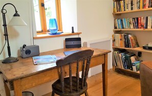 Desk with bookcase and large library of books and games to play.
