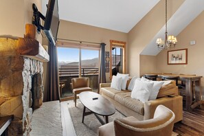 The living area features a gas fireplace, mounted flat-screen TV, and access to the private balcony.