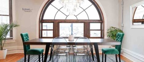 The dining room is the star of the show at The Loft Above featuring a 30” crystal chandelier, large dining table, and designer Louis Ghost chairs. 