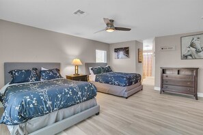 The large master bedroom has 2 queen beds, a dresser, a nightstand and Smart TV.