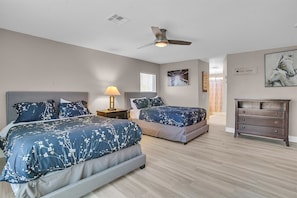 The large master bedroom has 2 queen beds, a dresser, a nightstand and Smart TV.