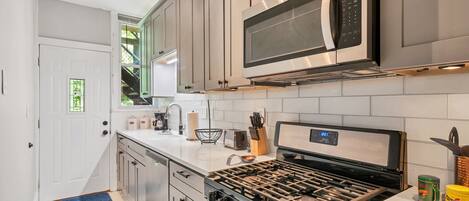 Beautiful kitchen with new stainless steel appliances and quartz countertop.