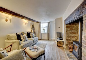 Attractive beamed living room with a woodburner in an inglenook providing a cosy focal point