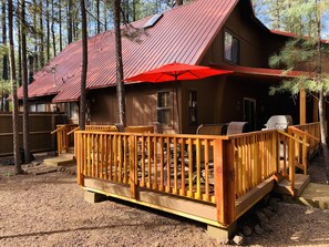 Large wrap around deck in backyard with 2 tables and a BBQ.