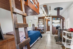 Charming interior with bunk beds, wood-burning stove, and cozy dining area-perfect for a unique and rustic getaway.