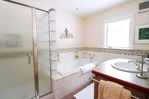 En-suite master bath with glass-enclosed shower and deep soaking tub.