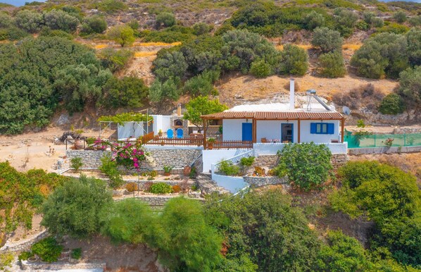 The house is perched on a hillside amidst olive trees