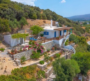 The house is perched on a hillside amidst olive trees