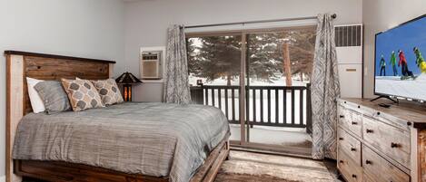 Serene queen bed next to charming outdoor patio, perfect for relaxation.