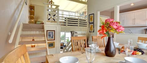 Dining area with view of the kitchen, open tread stairs lead to additional seating area with TV.