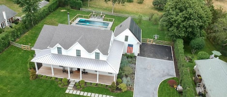 Drone view of property, fenced gunite pool and beautiful field beyond