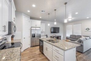 Kitchen Side View - The kitchen is fully stocked with all the dishes, cookware, baking pans, and cutlery you will need for meal preparations and includes stainless steel appliances and granite counter tops.