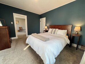 Main level bedroom with queen bed, hanging rack, dresser, floor length mirror.
