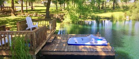 Pond area with dock, pedal boat, and paddle board.