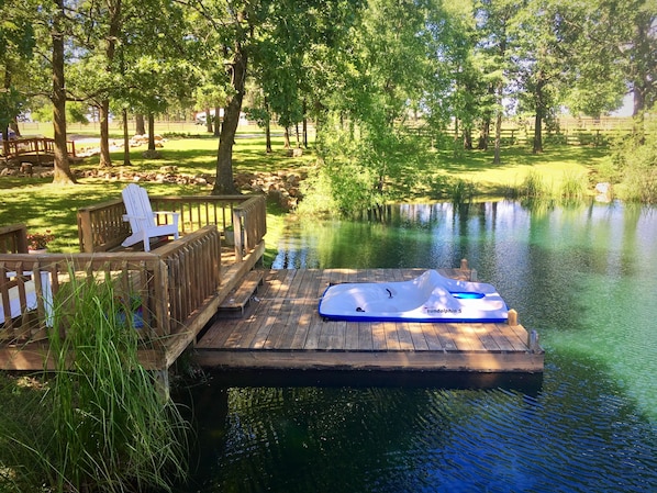 Pond area with dock, pedal boat, and paddle board.