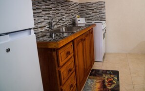 Kitchen with electric stove, microwave, fridge. Toaster, kettle .