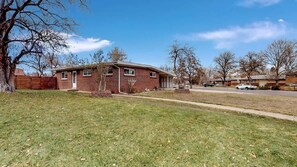 Spacious side yard with a well-maintained lawn, mature trees, and a charming brick home in a peaceful neighborhood.