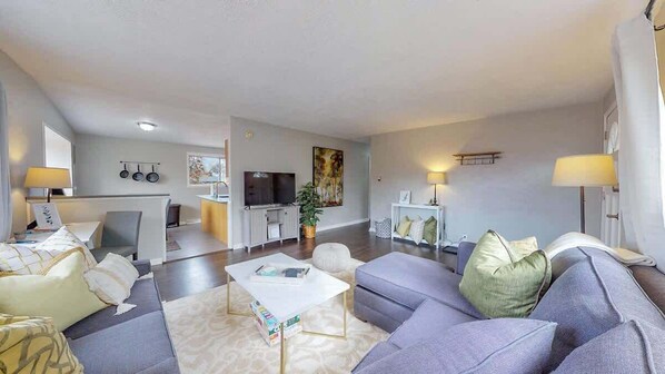 Stylish and cozy living area with a plush sectional, warm lighting, and modern decor. The open layout connects seamlessly to the kitchen, creating a welcoming space for relaxation and entertainment.