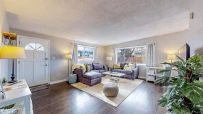 Stylish and cozy living area with a plush sectional, warm lighting, and modern decor. The open layout connects seamlessly to the kitchen, creating a welcoming space for relaxation and entertainment.