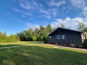 View from parking area into backyard, pond in distance.